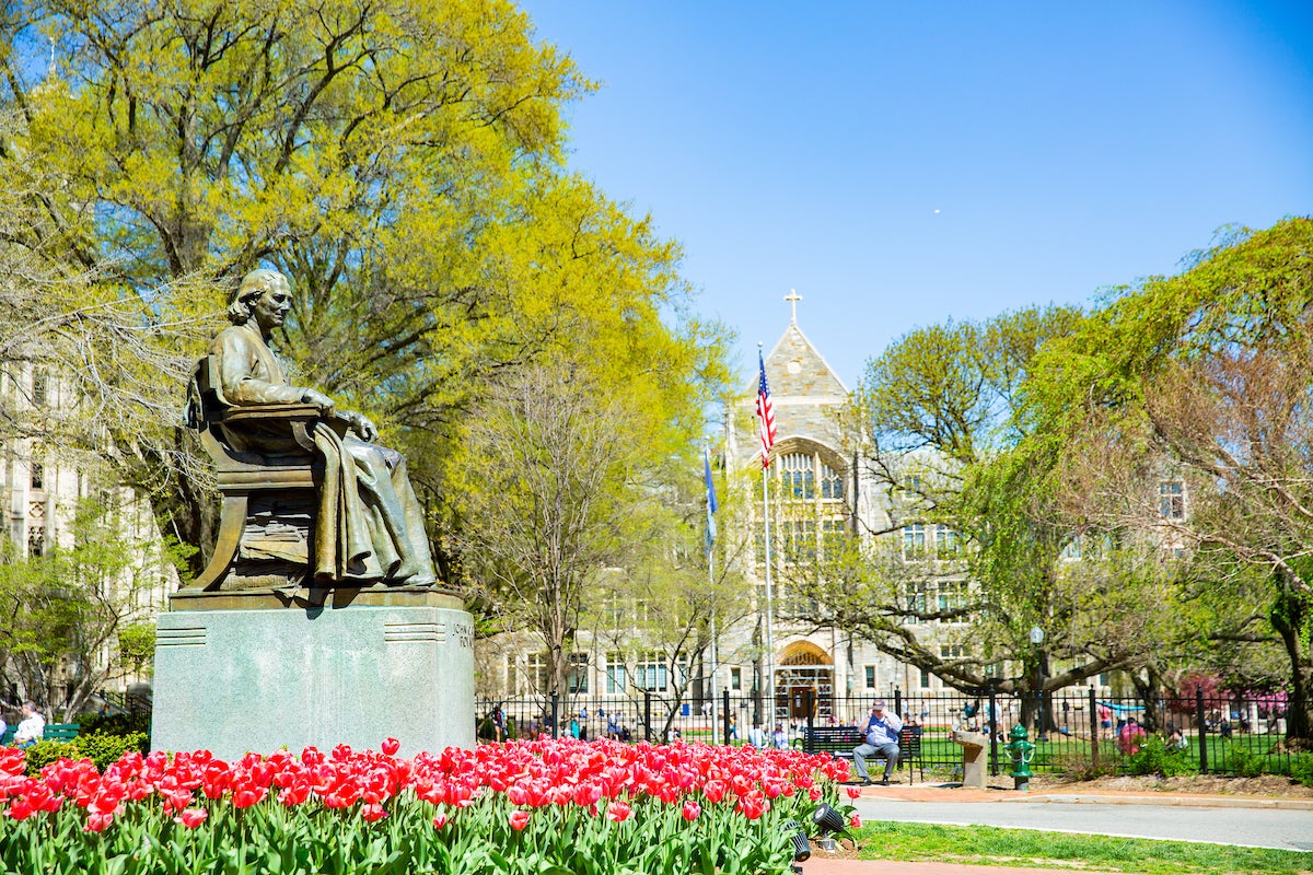 Statue of John Carroll in front of Healy Hall surrounded by red tulips