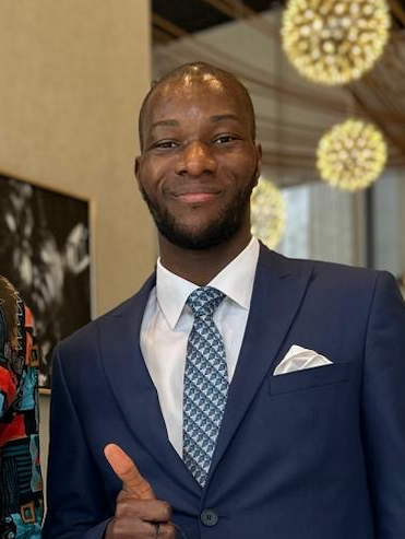 Chriss Jordan Oboa Franck wearing a navy suit and a tie.