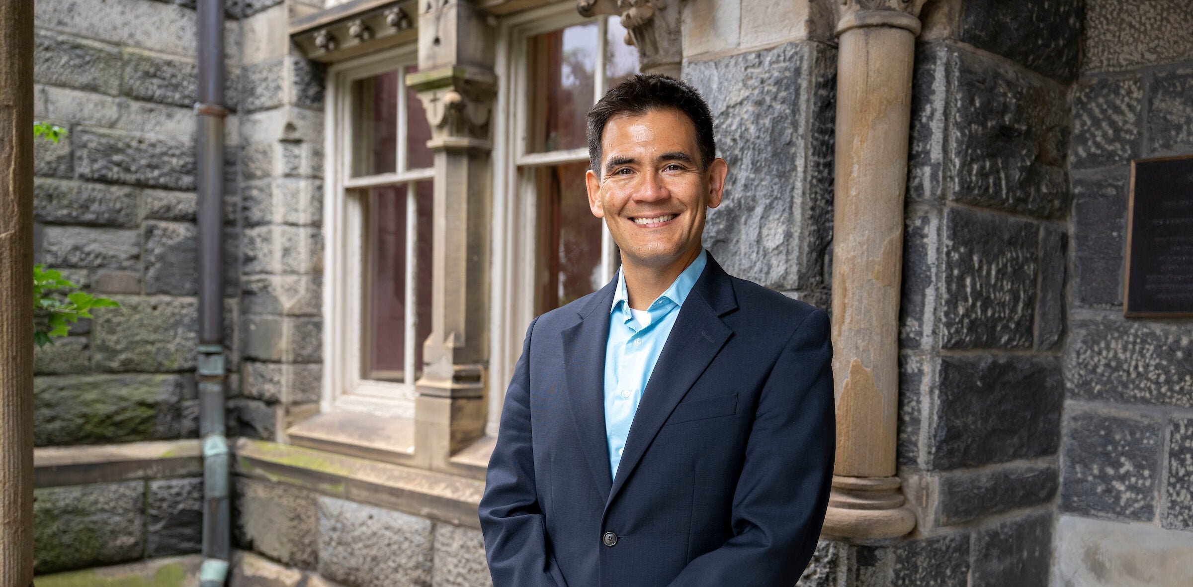 Prof Yoshi Kohno stands in front of a building
