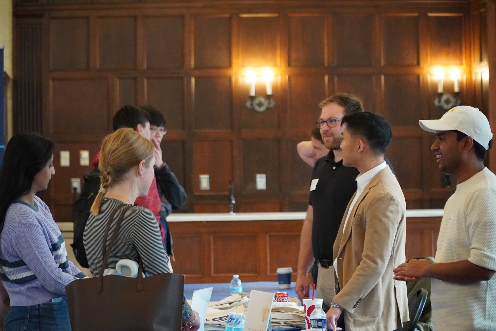 Students and employers stand across from each other at a table and talk.