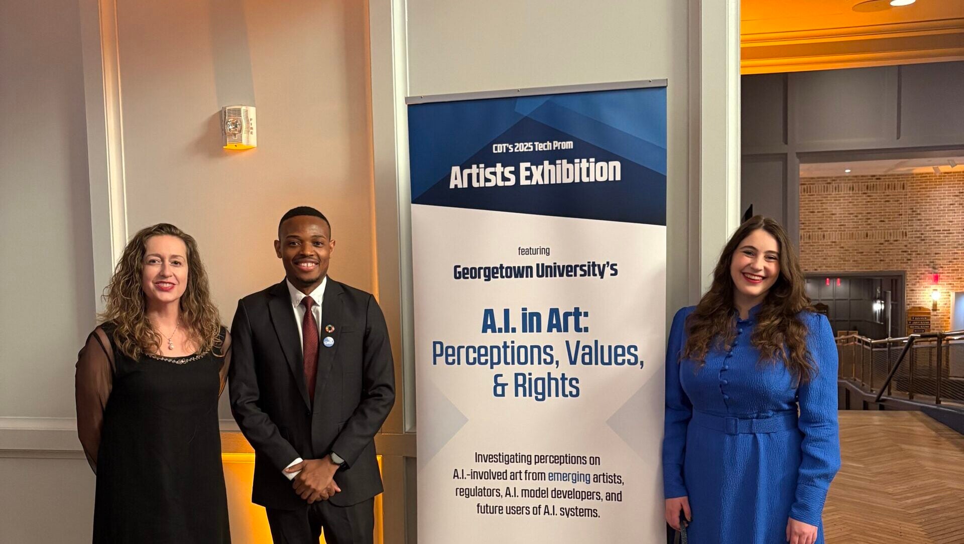 Professor Toni-Lee Sangastiano, PhD student Wisdom Obinna, and Professor Elissa Redmiles pose in front of Ai in Art banner at CDT's 2025 TechProm