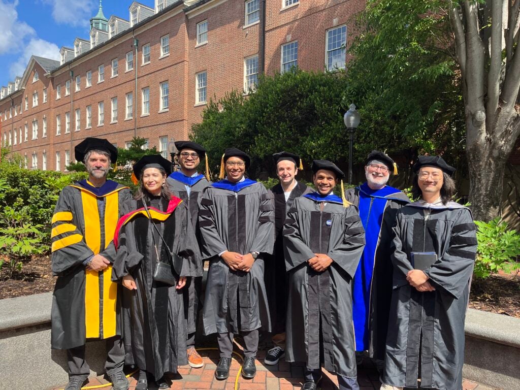 CS PhD students and faculty pose in commencement attire outside