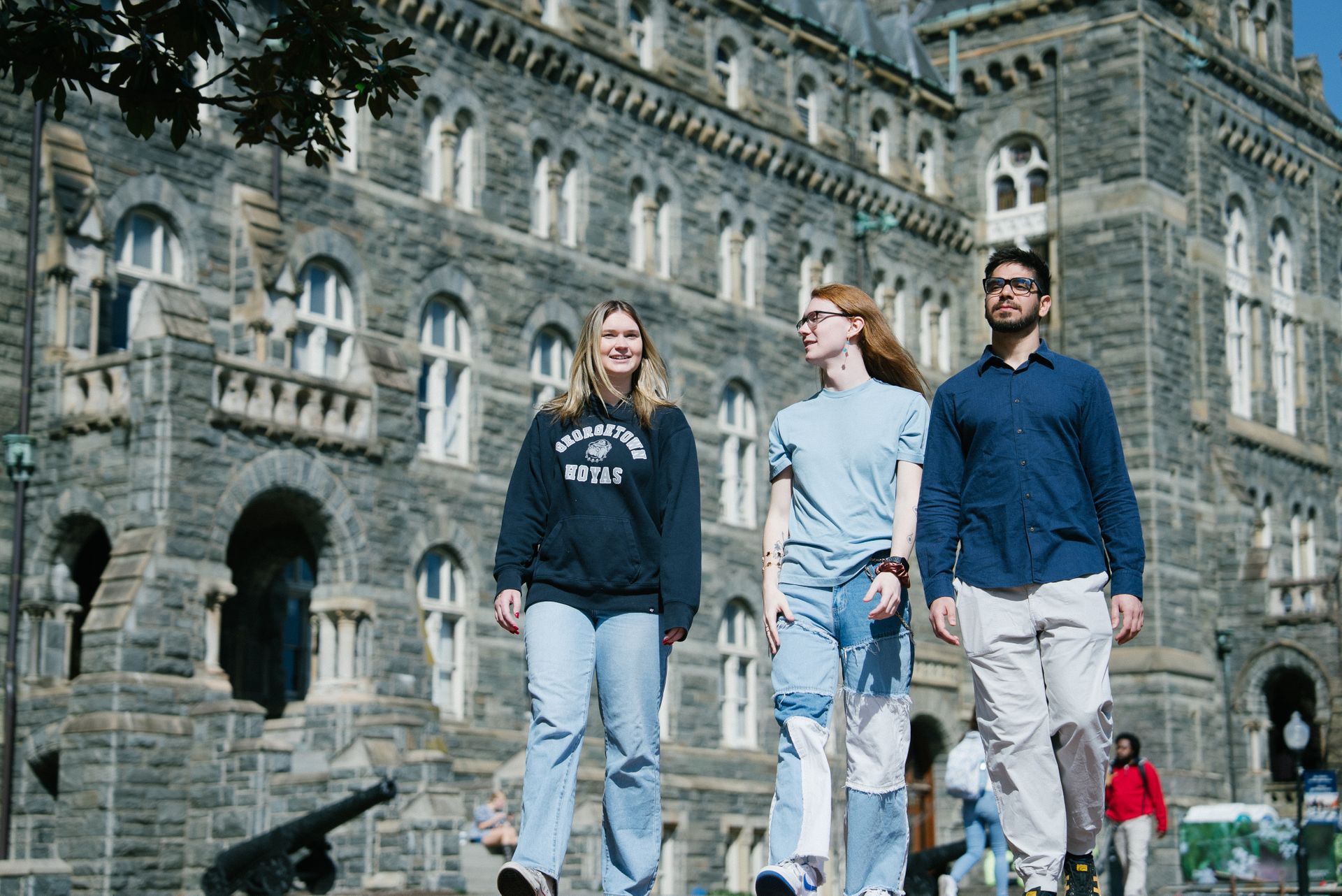 Three students walking and talking in front of Healy Hall.