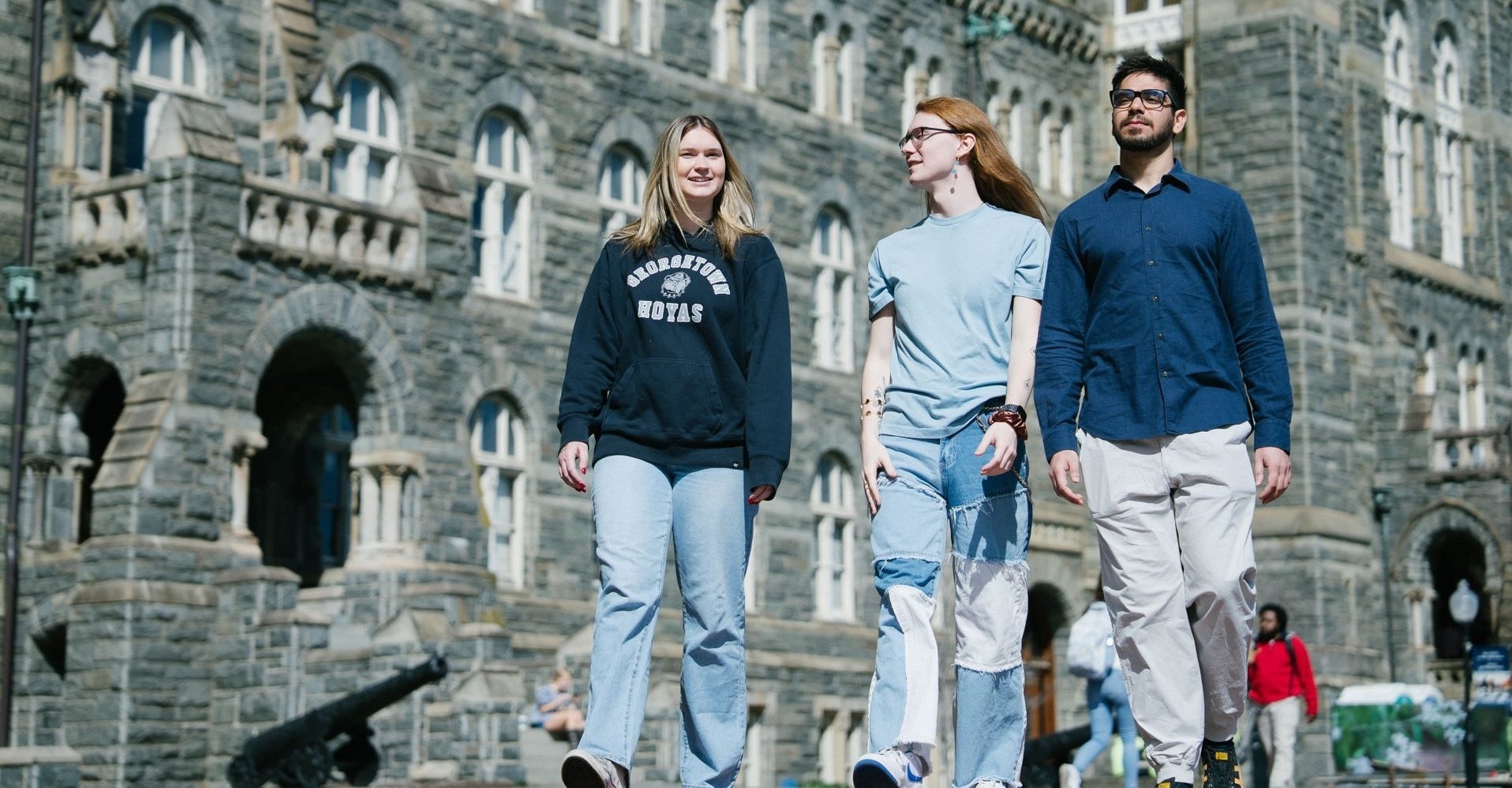 Three students walking and talking in front of Healy Hall.