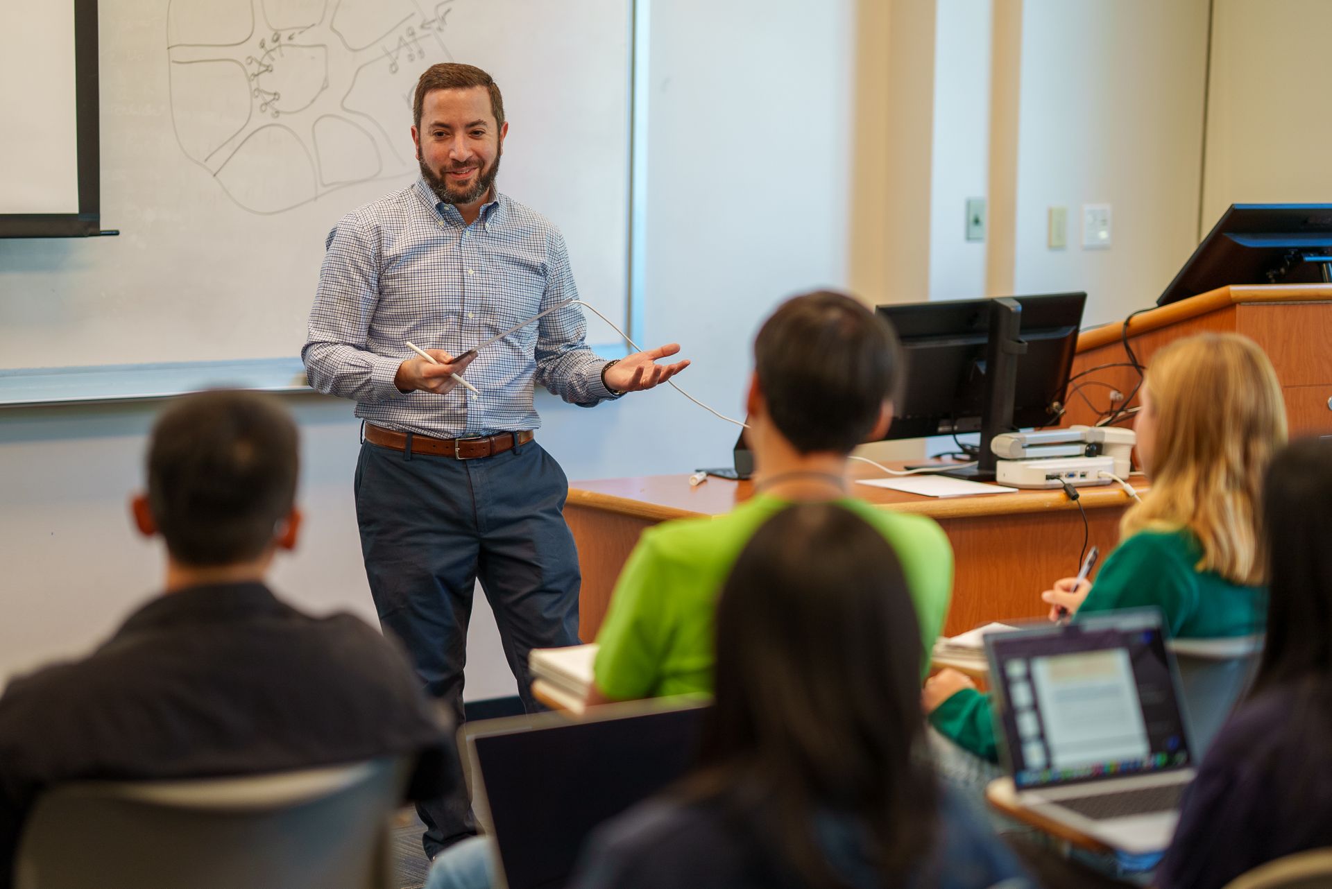 A professor stands in front of the room and teaches a class.