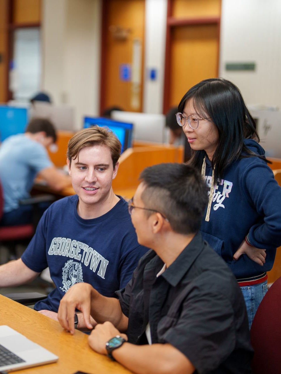 Three students working together at a computer in the library.